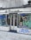 A storefront with graffiti-covered windows and doors, featuring various abstract designs and doodles in multiple colors. The sign above the store reads 'A Deusa'. The ground is covered in cobblestone pavement.