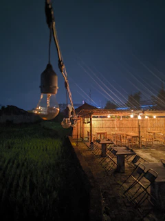 Evening view of the restaurant’s exterior with warm lighting and bamboo accents, set against a twilight sky.