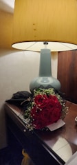 Nightstand with a reading lamp and a small vase of fresh flowers.