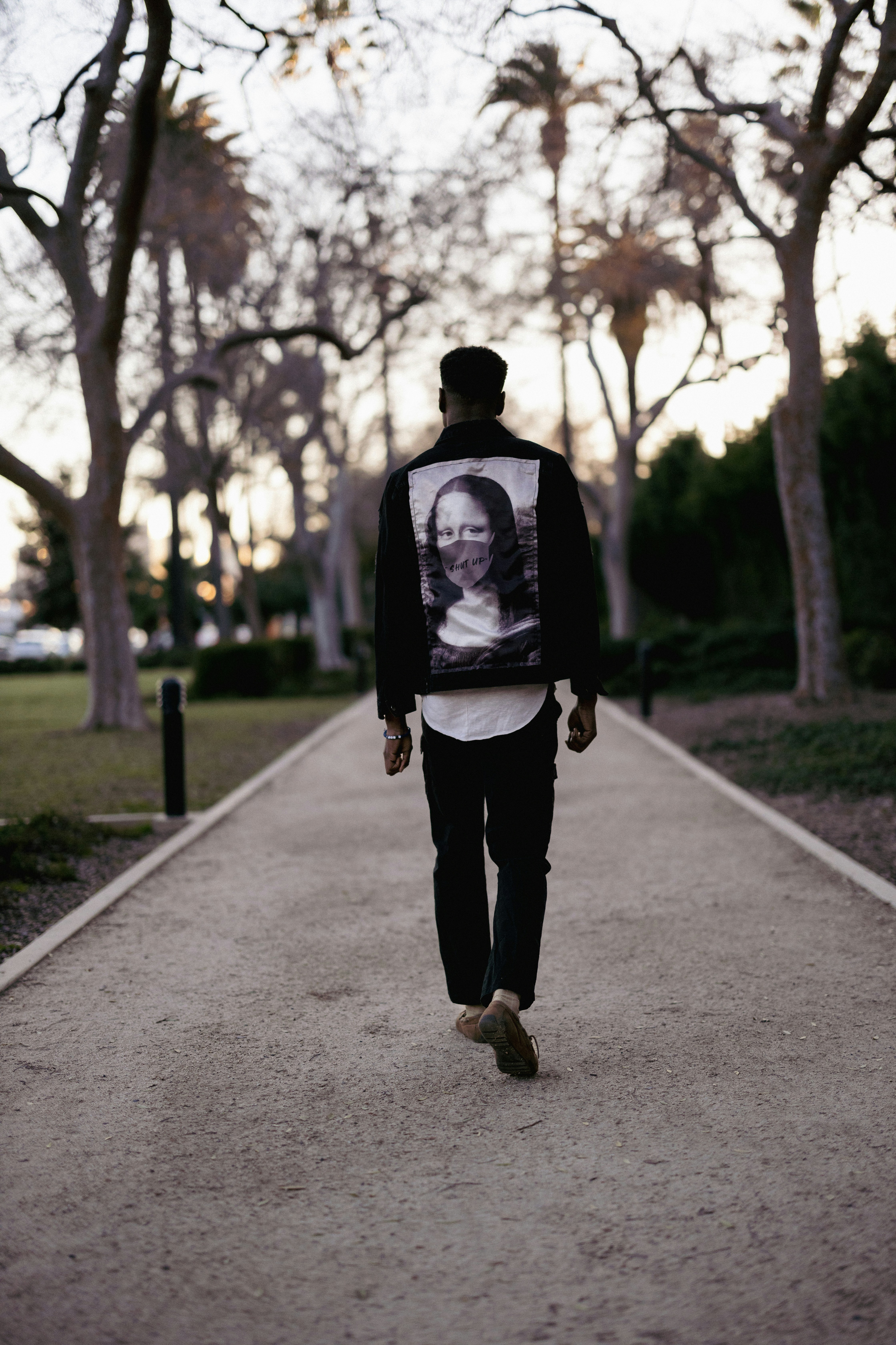 a man walking down a sidewalk with trees in the background