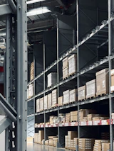 A modern warehouse with neatly stacked FMCG goods illuminated by ambient galaxy-inspired lighting.