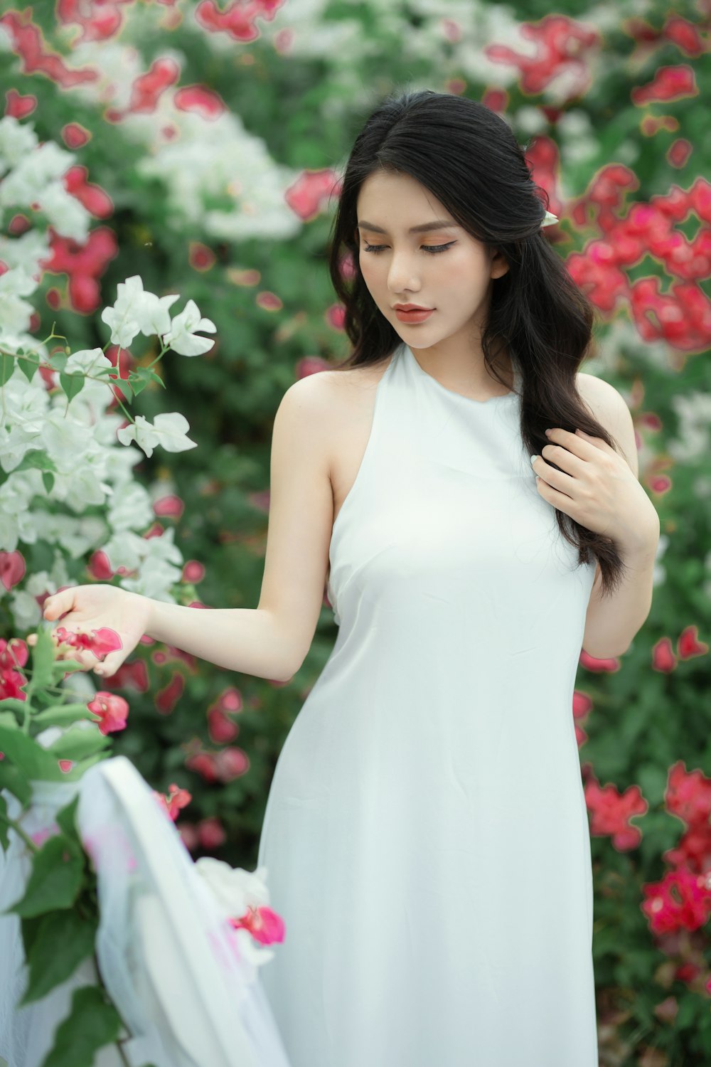 Una mujer con un vestido blanco parada frente a las flores