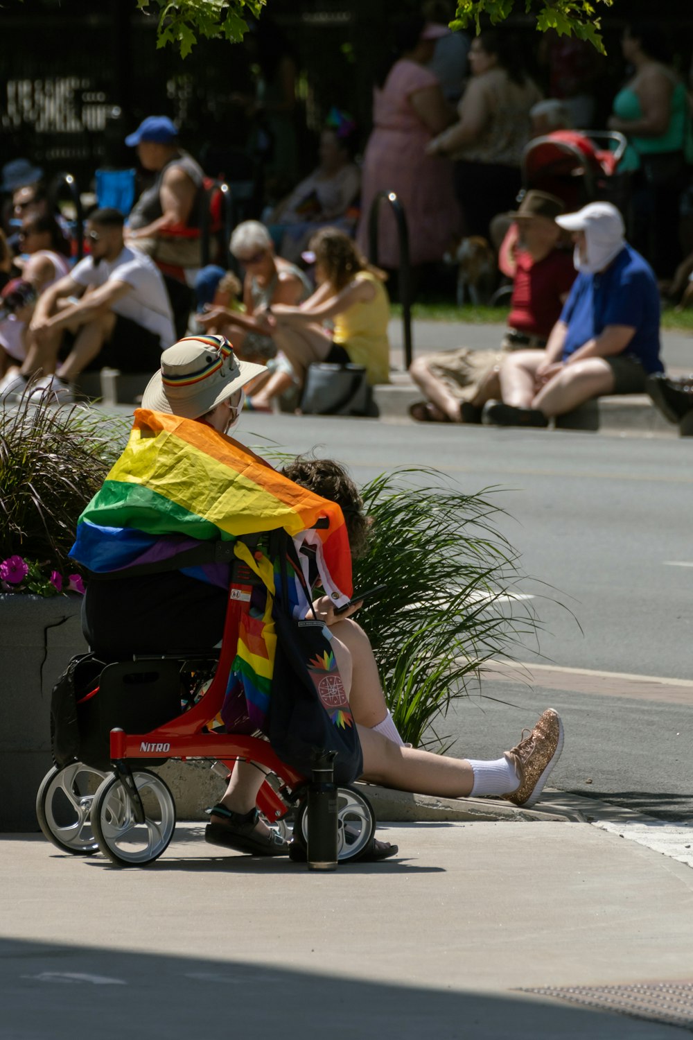 a man in a wheelchair with a rainbow flag draped over his shoulders