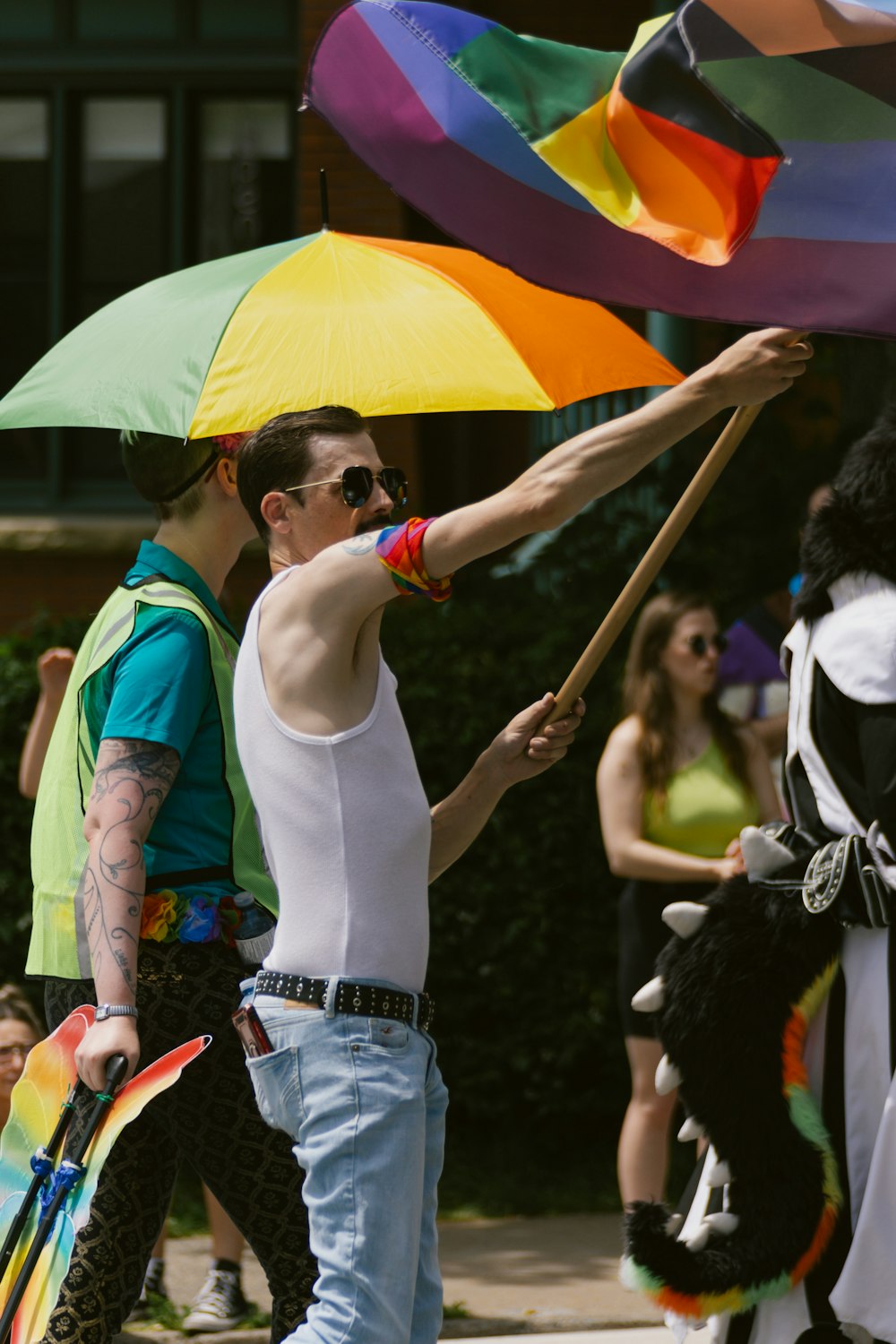 a man holding a rainbow umbrella in a parade