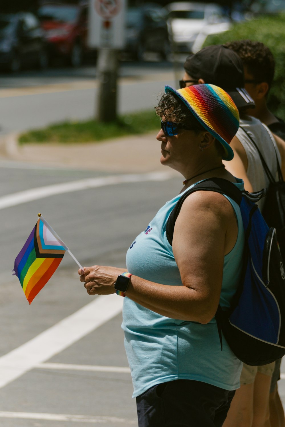 a woman holding a rainbow colored kite on the street