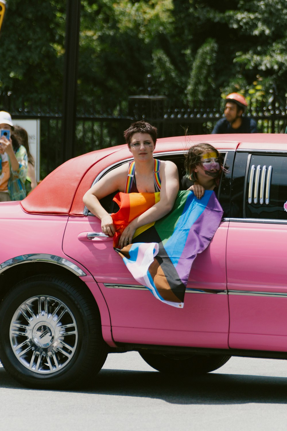 a woman in a bikini sitting on the back of a pink car