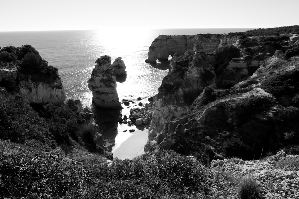 a black and white photo of the ocean and cliffs