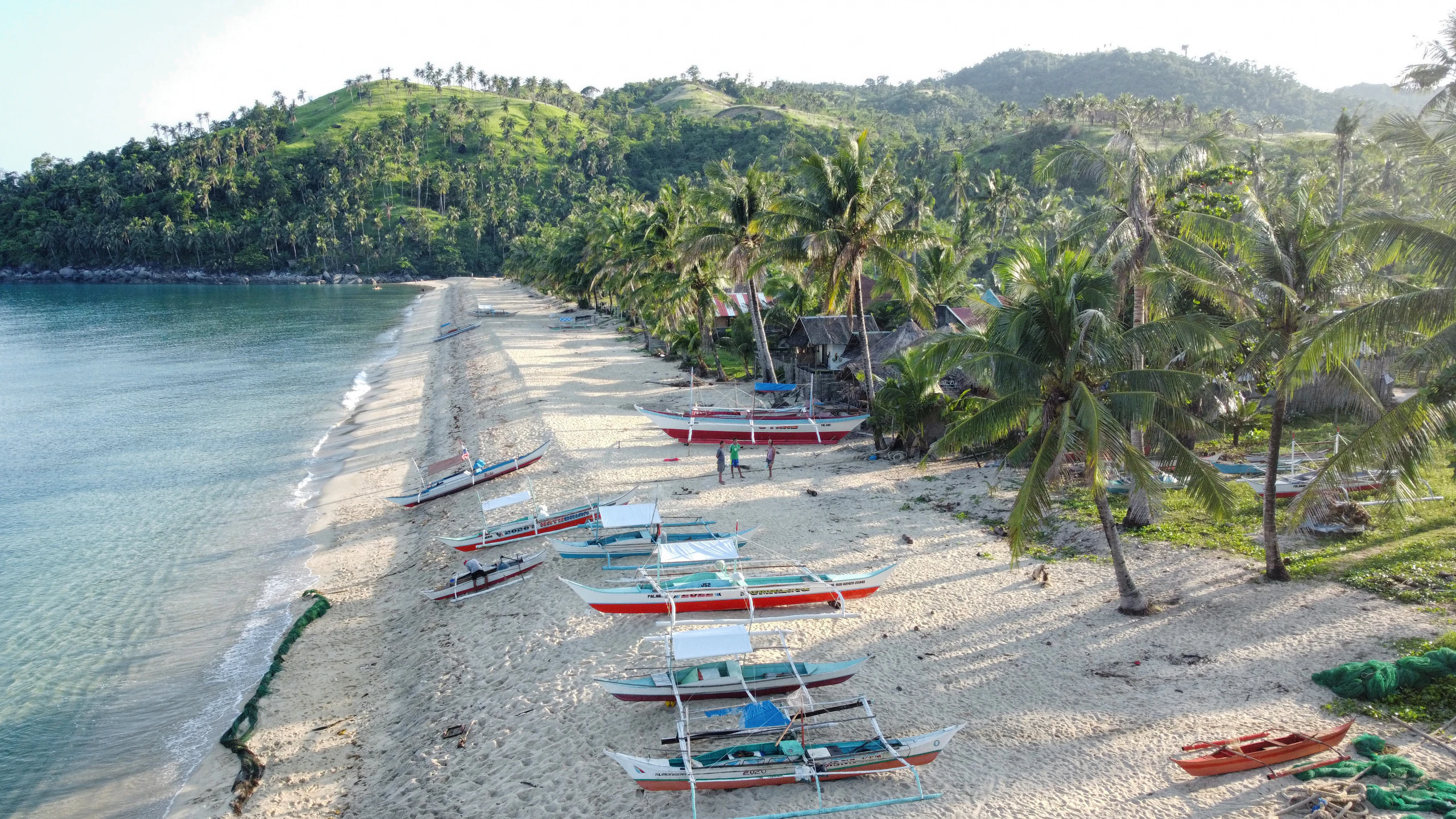 Outrigger boats pulled up on a sandy beach in Palawan