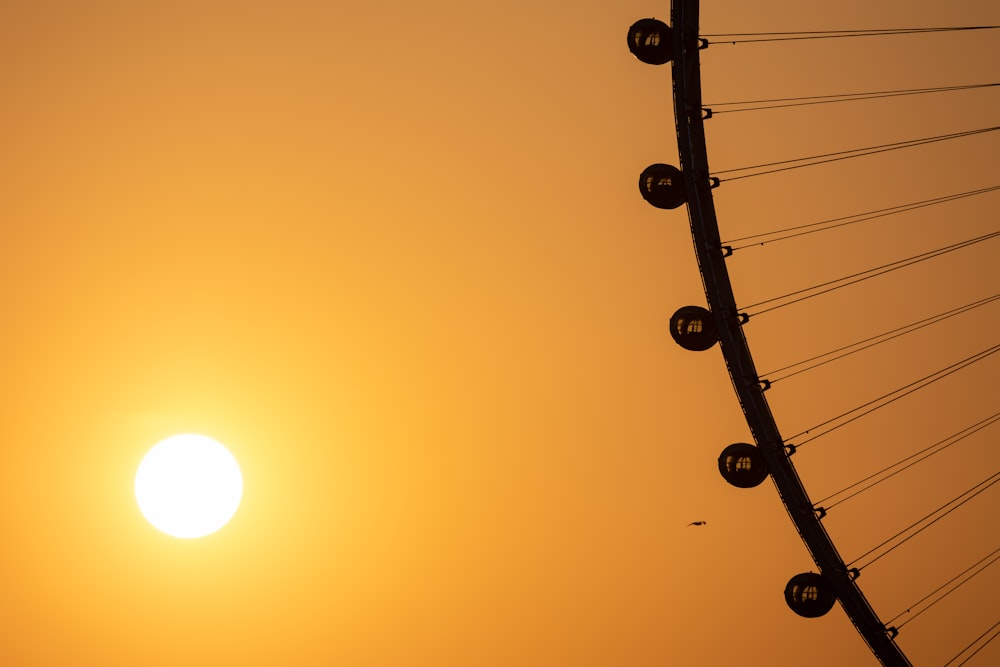 the sun is setting behind a ferris wheel