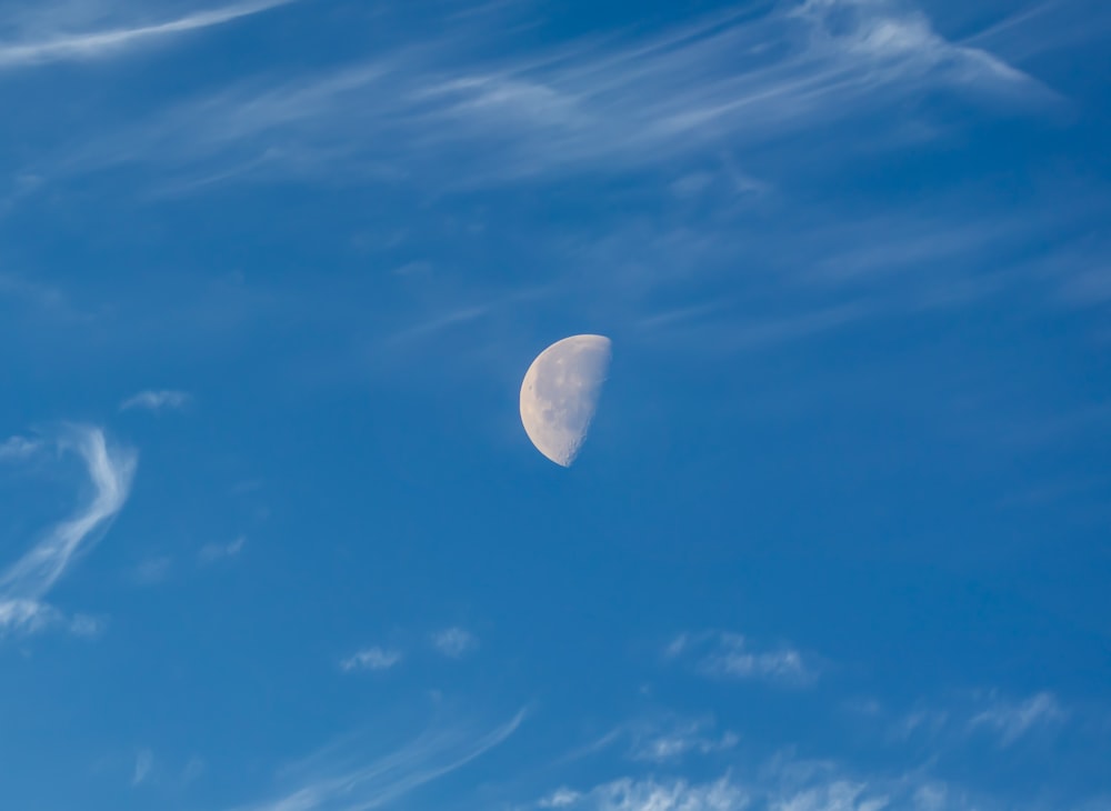 a half moon in a blue sky with clouds