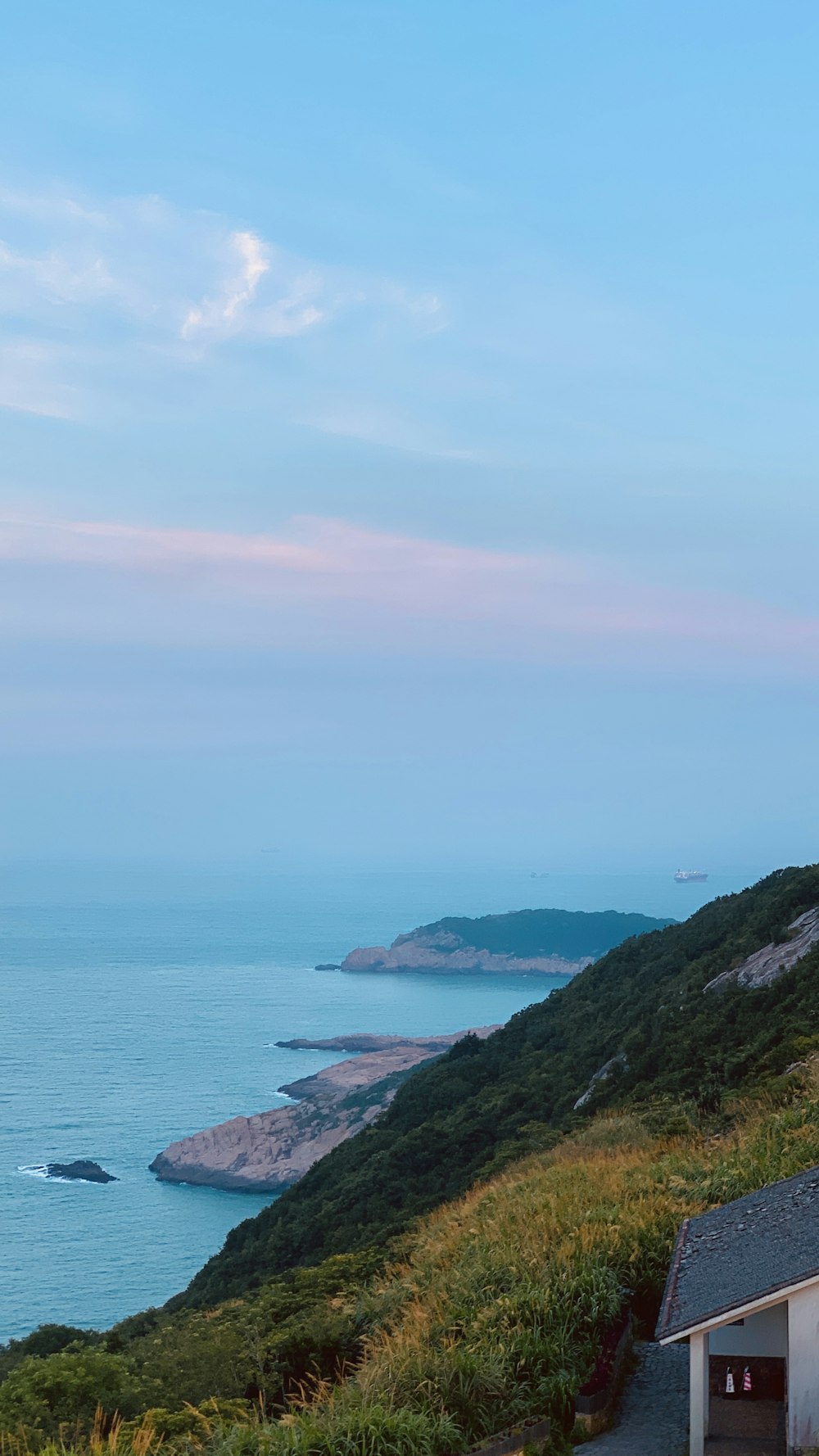 a house sitting on top of a hill next to the ocean