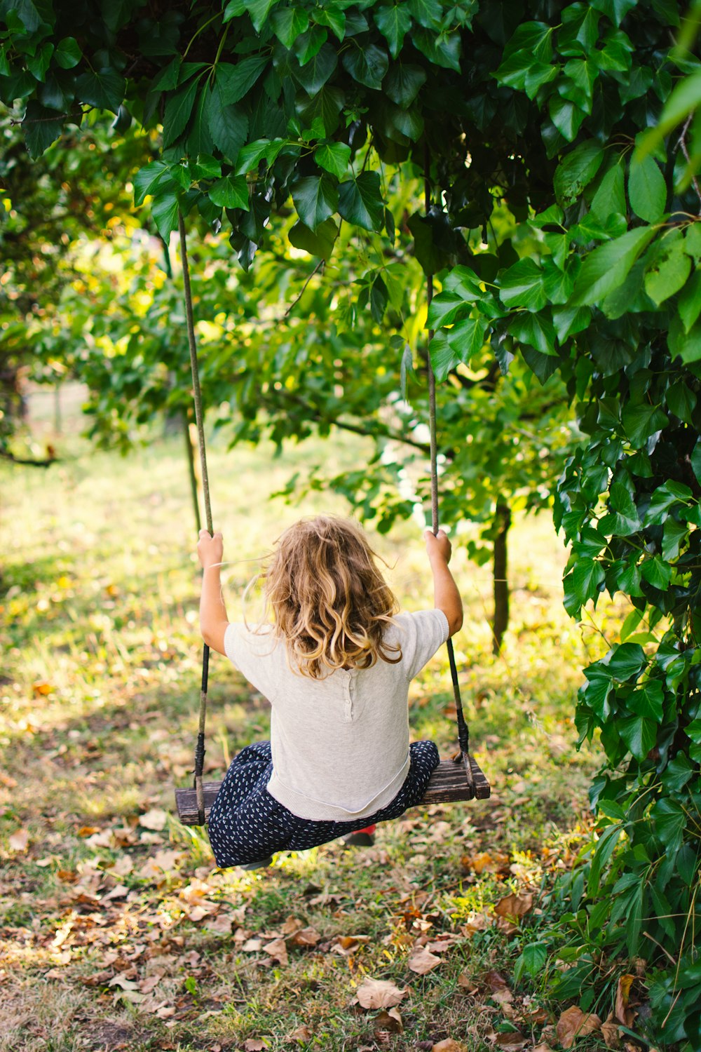 a little girl sitting on a swing in a tree