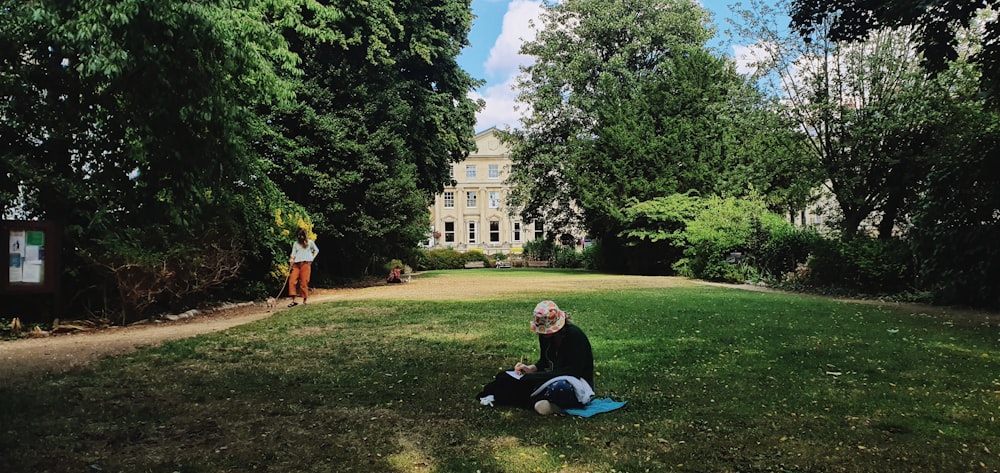 a person sitting in the grass in front of a building