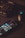 A smartphone displaying various social media app icons is placed on a dark surface. Nearby, a gaming mouse with a glowing logo and a mechanical keyboard with illuminated keys are visible. The lighting is low and focused, creating a moody atmosphere.