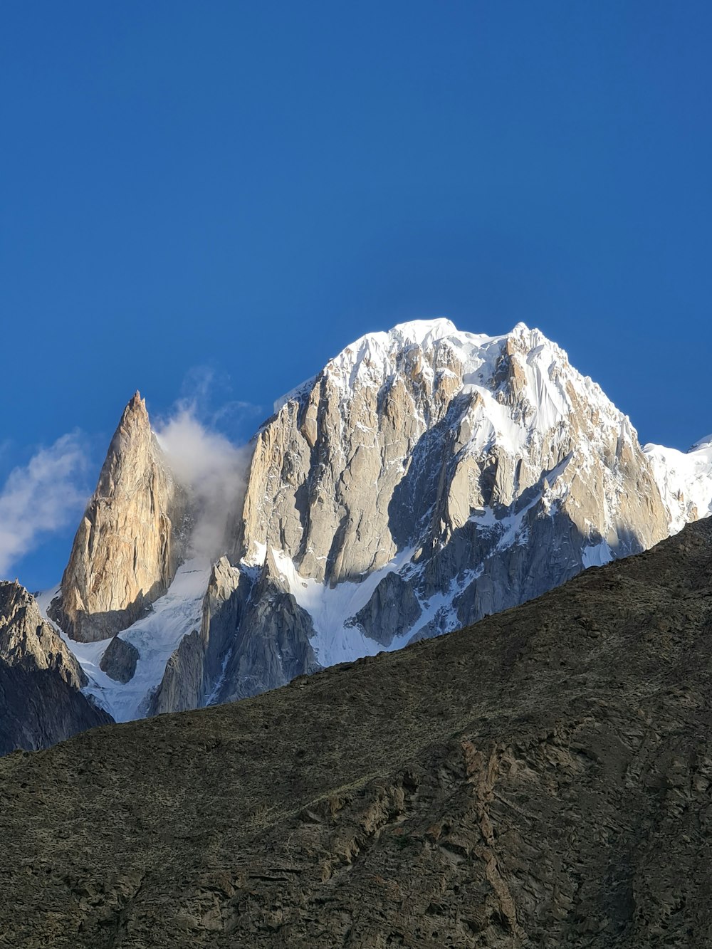 a snow covered mountain with a cloud in the sky