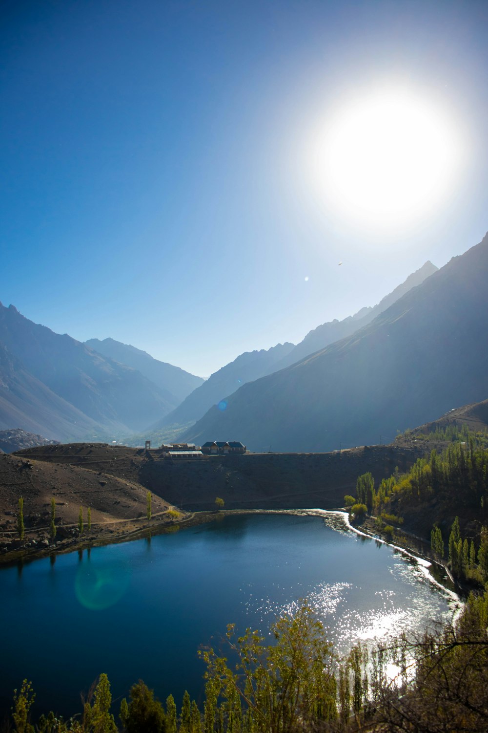 the sun is shining over a mountain lake