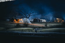 Night view of a camping site with glowing lights and happy families.