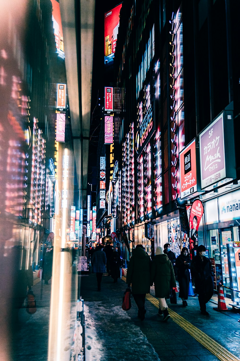 a group of people walking down a street next to tall buildings