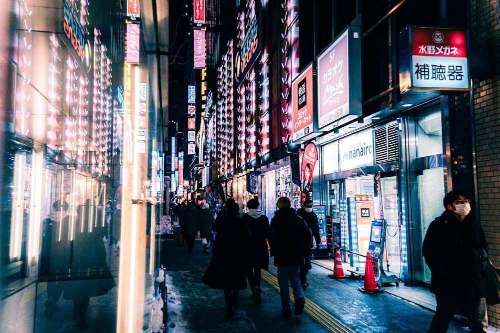 a group of people walking down a street next to tall buildings