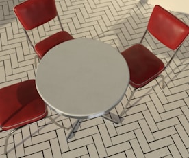 a round table with four red chairs around it
