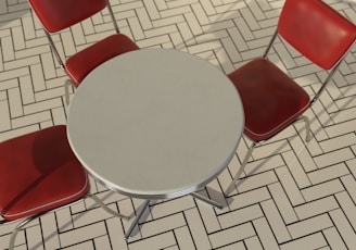 a round table with four red chairs around it