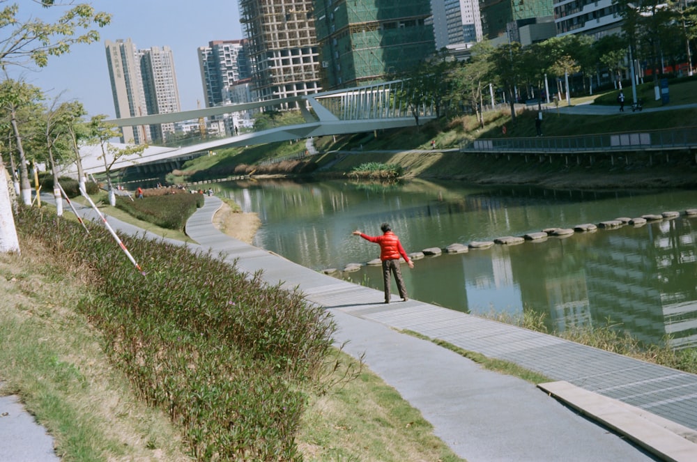 a man standing on a sidewalk next to a river