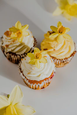 Two young girls helping to decorate cupcakes with bright frosting and edible flowers.