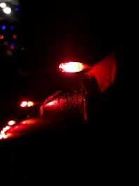 Several red LED lights are illuminated against a dark background, positioned closely along a horizontal surface, creating a dramatic contrast with the dark surroundings.