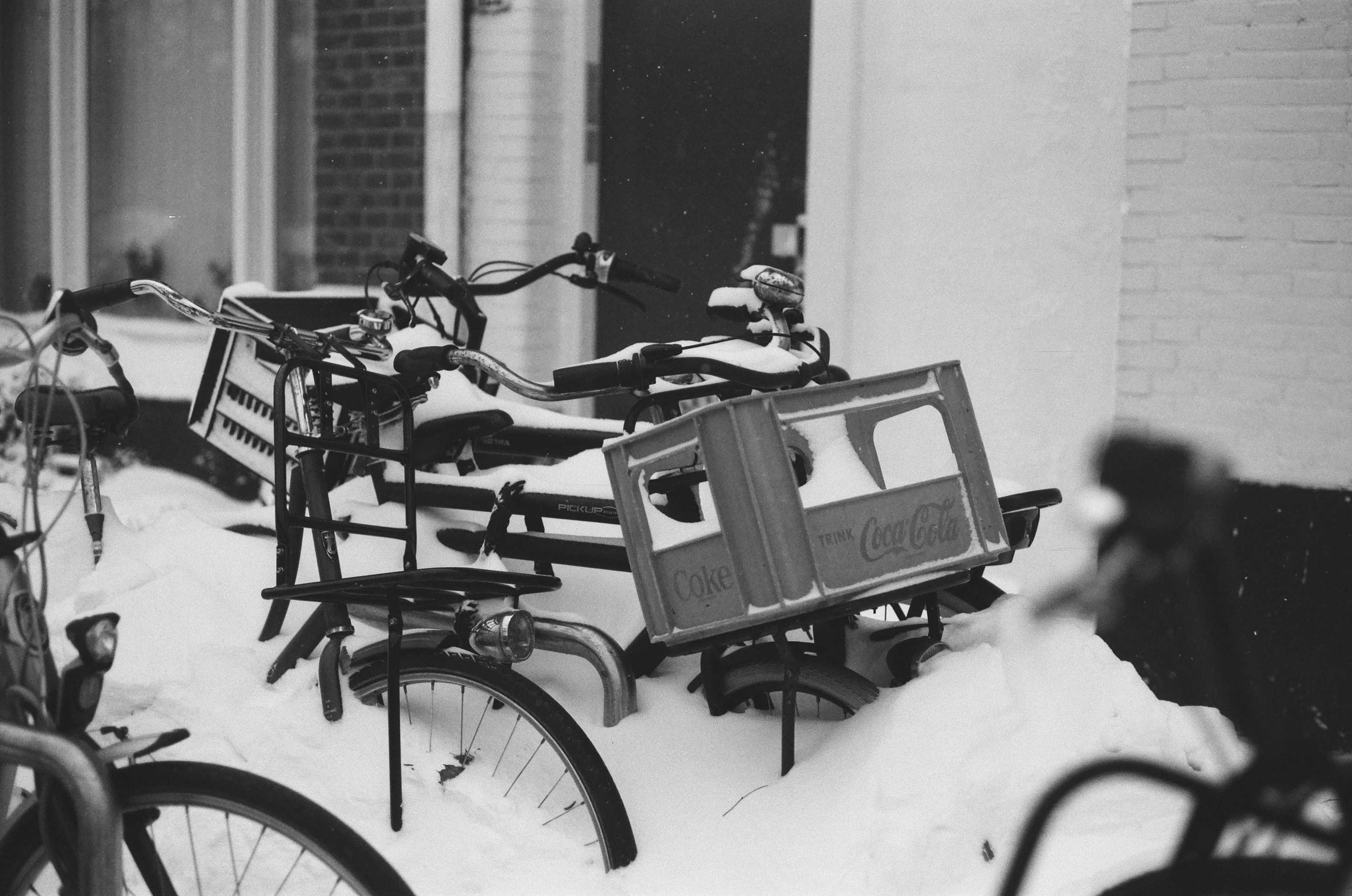 a black and white photo of bicycles parked in the snow, 