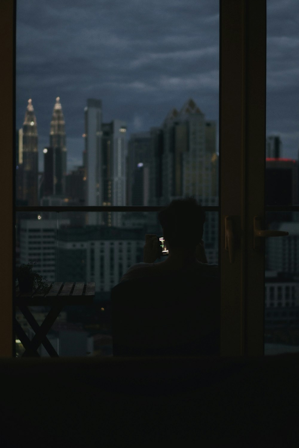 a person sitting in a chair looking out a window at a city