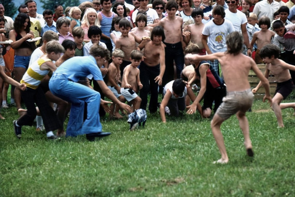 a group of children playing with a frisbee in front of a crowd of