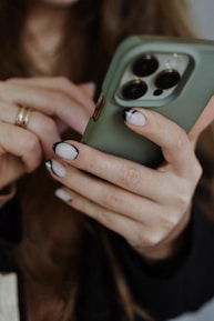 Close-up of hands holding a smartphone with pastel green and pink background.