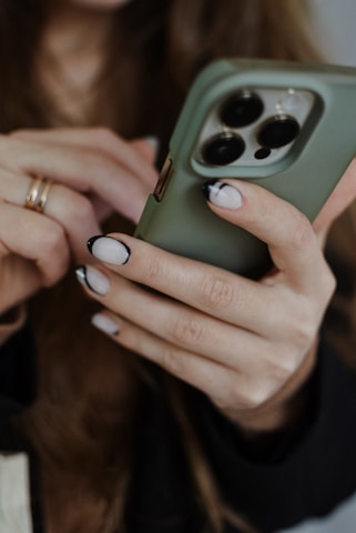 Close-up of hands holding a smartphone with pastel green and pink background.