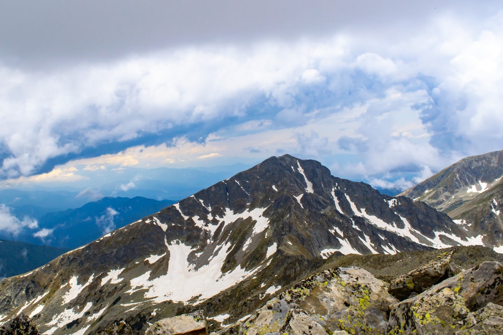 a snow covered mountain range under a cloudy sky