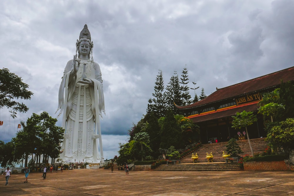 a large white buddha statue sitting in the middle of a park