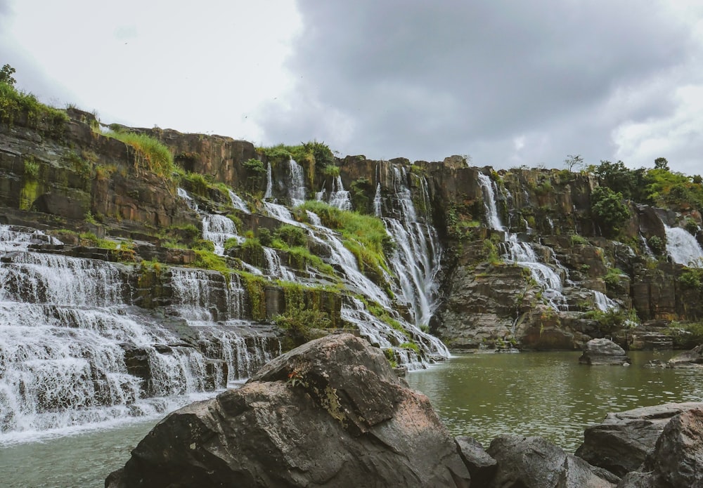 a waterfall with a large rock in front of it