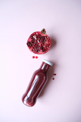 Brightly colored pomegranate-beetroot juice bottle splashing with fresh fruit around