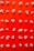 Popcorn is neatly arranged in a grid pattern on a bright red background, creating a visually striking contrast. Each kernel is distinct, with different shapes and sizes, highlighting the irregular nature of popcorn.