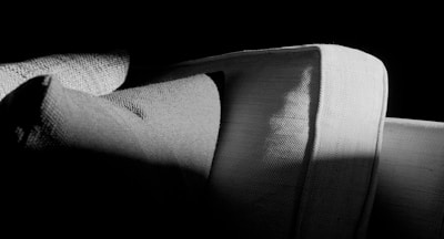 Close-up of natural linen cushions on a handcrafted wooden sofa in soft light.