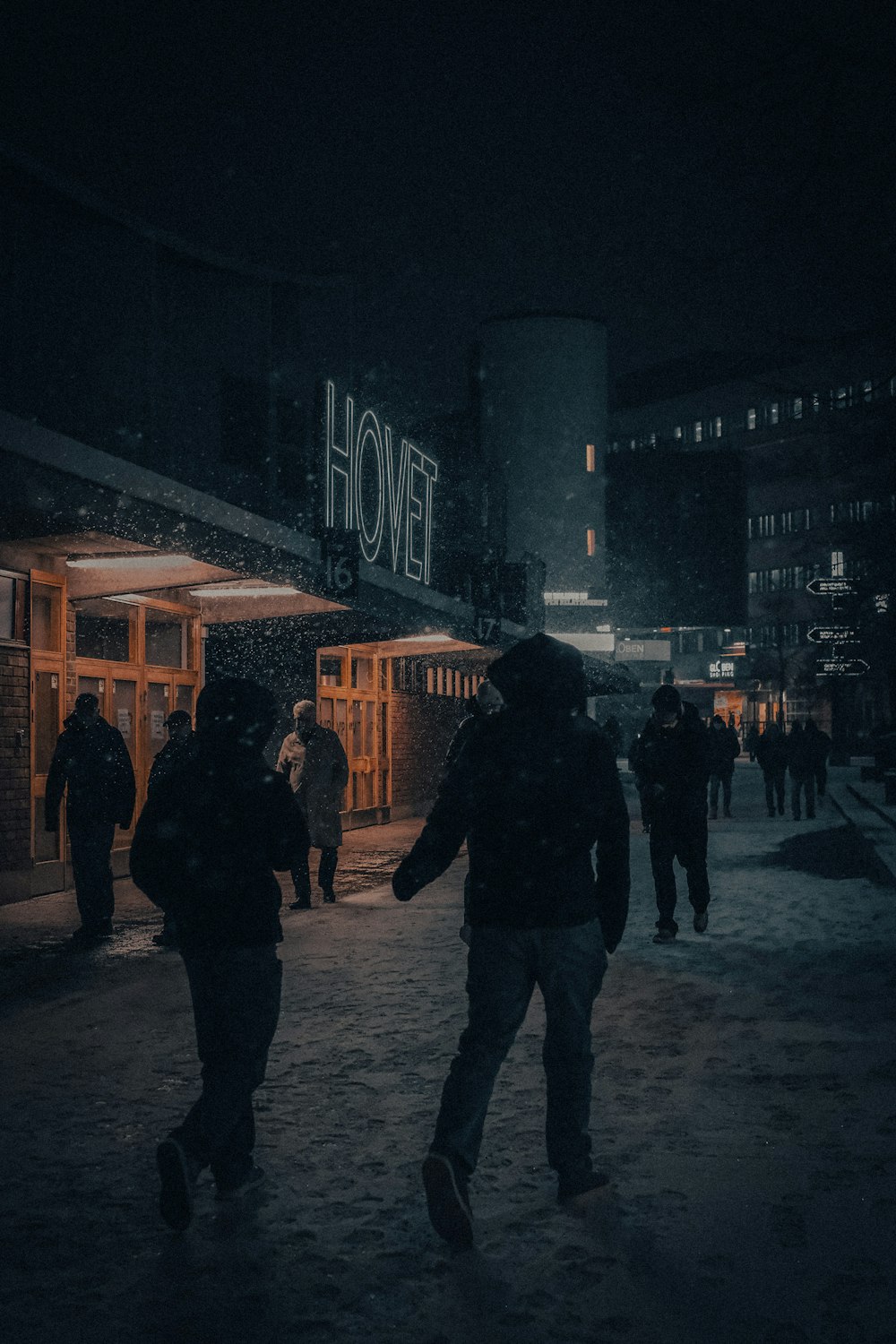 um grupo de pessoas andando por uma rua à noite