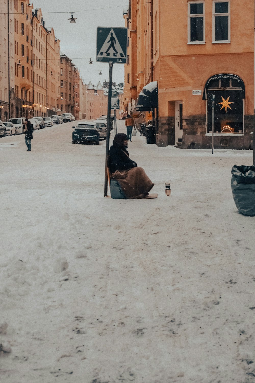 a person sitting in the middle of a snowy street