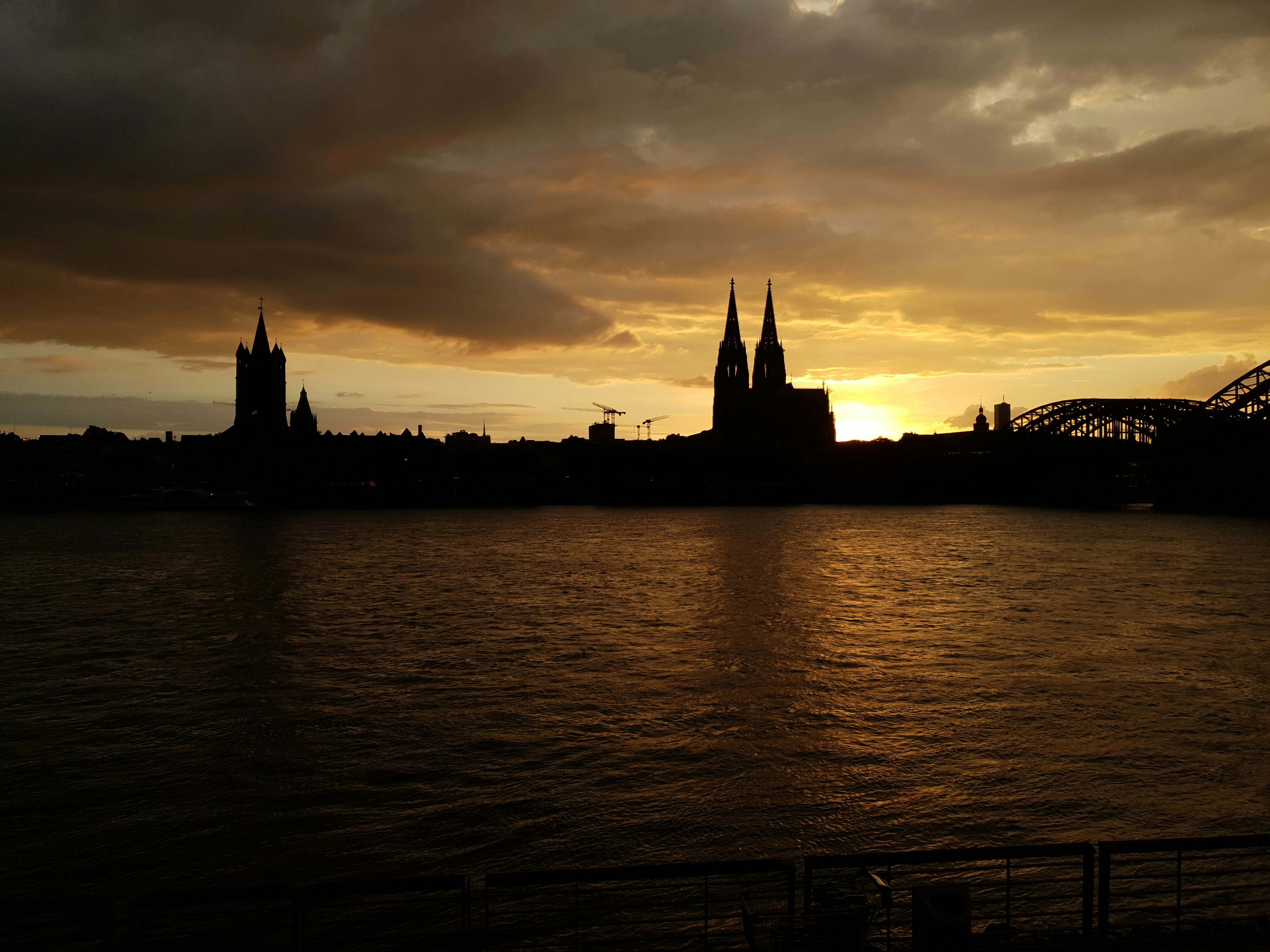 Cologne city panorama at sunset, Rhine river, cathedral towers, golden hour light, wide aerial view