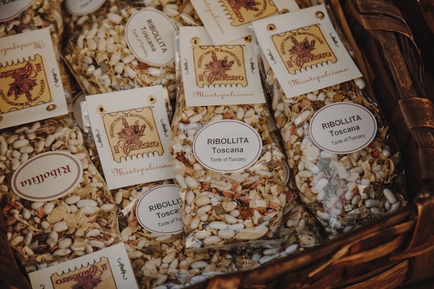 Several packages of dried Ribollita soup mix are displayed in a wicker basket. The packages contain a mix of beans, vegetables, and spices, and are labeled with details indicating they originate from Tuscany.