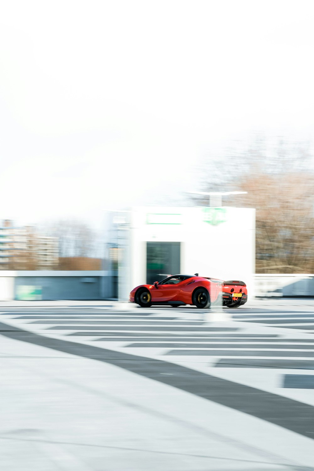 a red sports car driving past a white building