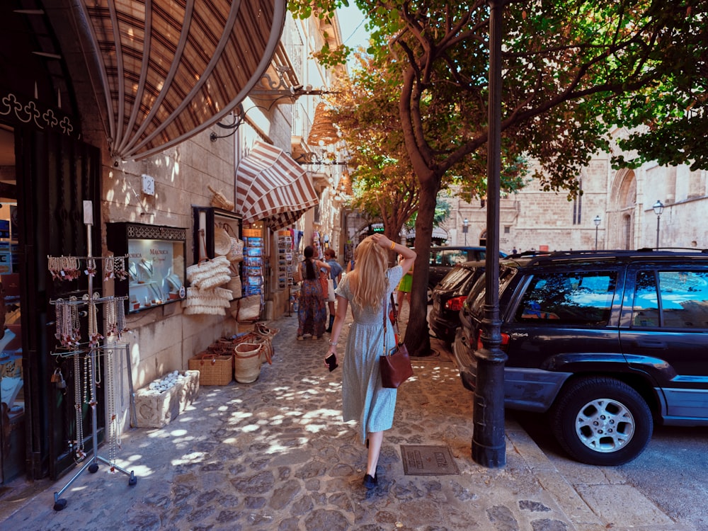 a woman walking down a street next to a car