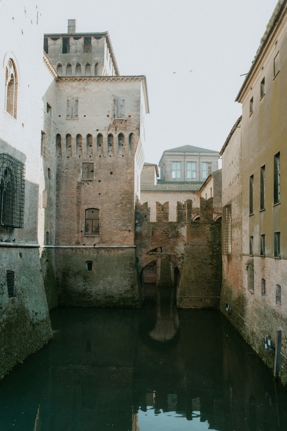 a narrow canal in a city next to tall buildings