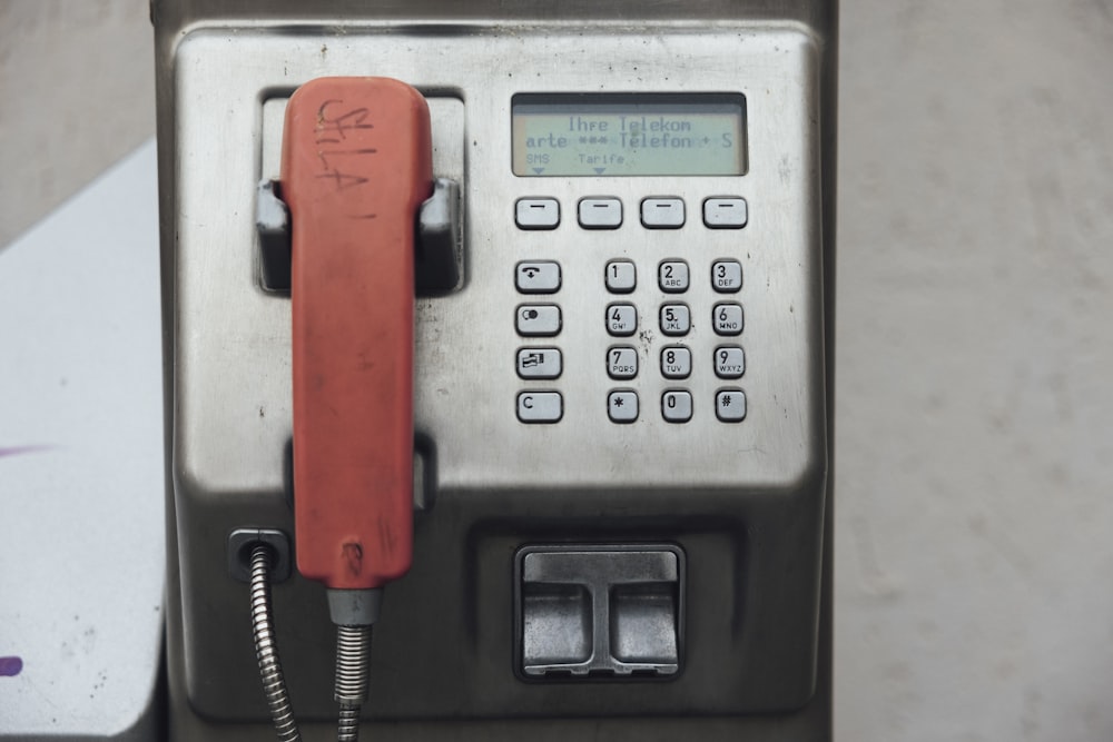 an old style pay phone with a red dial