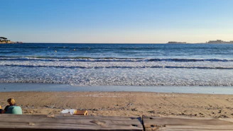 a person sitting on a beach next to the ocean