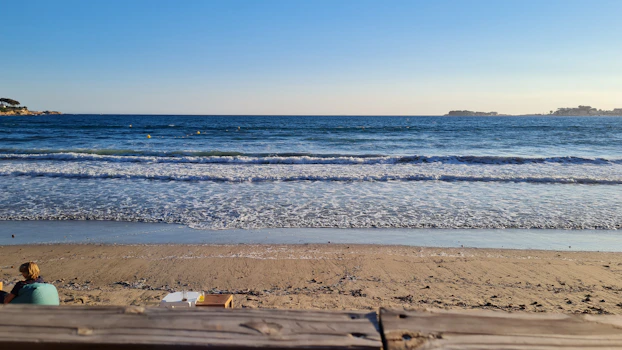a person sitting on a beach next to the ocean