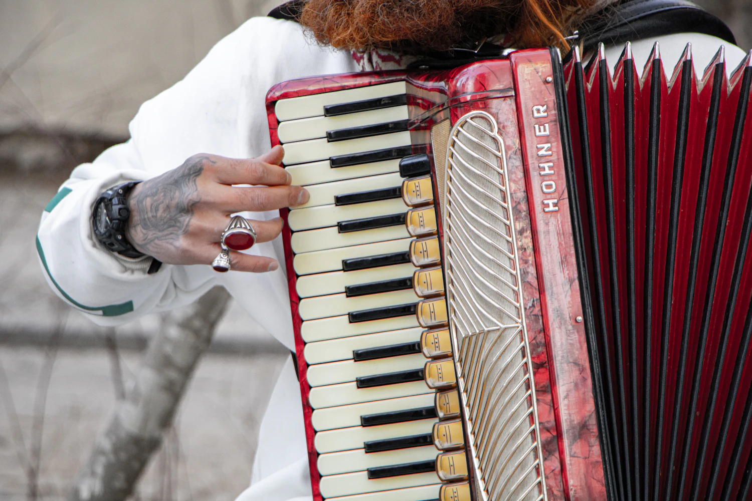 Close-up of hands on the keys of a red piano accordion
